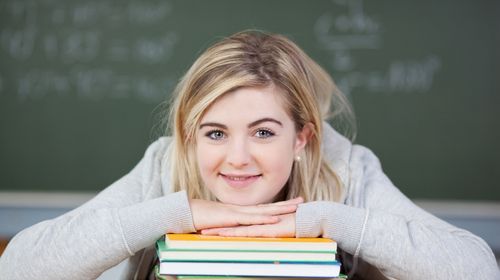 Blonde Lehrerin mit Bücherstapel